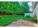 Private backyard featuring a brick patio, lush lawn, mature trees, and a white fence at 5045 Homeplace Dr, Apex, NC 27539