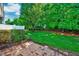 An inviting backyard featuring a lush lawn, mature trees, and a charming brick patio at 5045 Homeplace Dr, Apex, NC 27539