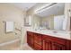 Dual vanity bathroom with cherry-stained cabinets, generous mirror and lighting at 5045 Homeplace Dr, Apex, NC 27539