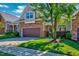 Inviting townhome featuring a two-car garage, stone details, and lush green lawn at 5045 Homeplace Dr, Apex, NC 27539