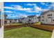 A lush backyard with a wood fence, green lawn, and view of neighborhood homes under a bright, cloudy sky at 508 White Oak Branch Ln, Apex, NC 27523
