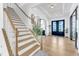 Elegant staircase with wooden handrail with a view of the front door at 508 White Oak Branch Ln, Apex, NC 27523