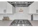 Close-up of a modern stainless steel stove top with white cabinets and hexagon backsplash at 508 White Oak Branch Ln, Apex, NC 27523