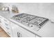 Close-up of a modern stainless steel stove top with white cabinets and hexagon backsplash at 508 White Oak Branch Ln, Apex, NC 27523