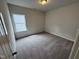 Cozy bedroom featuring neutral walls, plush carpeting, and bright natural light from a large window at 51 Commons Cir, Clayton, NC 27520