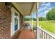 Inviting front porch with brick flooring, rocking chairs and a view of the front yard at 5136 Liberty Grove Rd, Liberty, NC 27298