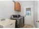Laundry room featuring modern washer and dryer with utility sink, exit door, and cabinet at 5136 Liberty Grove Rd, Liberty, NC 27298