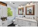 Bathroom with double vanity sinks, framed mirrors, and a window at 5409 Knollwood Rd Rd, Raleigh, NC 27609