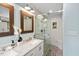 Bright bathroom featuring a double sink vanity with marble countertop and glass-enclosed shower with pebble flooring at 5409 Knollwood Rd Rd, Raleigh, NC 27609