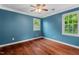 Stylish bedroom with hardwood floors, blue walls, a ceiling fan, and bright windows at 5409 Knollwood Rd Rd, Raleigh, NC 27609