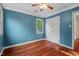 Welcoming bedroom with hardwood floors, blue walls, a ceiling fan, and bright windows at 5409 Knollwood Rd Rd, Raleigh, NC 27609
