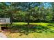 Backyard showing a sprawling lawn bordered by mature trees and glimpses of a wooden fence, all bathed in sunlight at 815 Solitude Pt, Chapel Hill, NC 27516