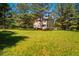Expansive backyard view with lush green lawn, framed by mature trees and a glimpse of the white house exterior at 815 Solitude Pt, Chapel Hill, NC 27516
