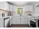 Well-lit kitchen featuring white cabinetry, stainless steel appliances, and hardwood flooring at 829 Burton St, Rocky Mount, NC 27803