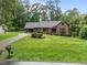 Charming brick home featuring a lush lawn, mature trees, and inviting curb appeal on a sunny day at 8509 Oneal Rd, Raleigh, NC 27613