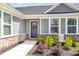 Charming home entrance with a purple door, stone accents, and a well-manicured garden with green bushes at 8615 Kenridge Ln, Fuquay Varina, NC 27526