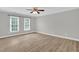 The empty bedroom has fresh paint and new flooring with two large windows and a ceiling fan with light fixture at 1003 Wicksteed Ct, Apex, NC 27502