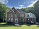 Beautiful two-story brick home with manicured lawn, mature trees, and inviting walkway to the front door at 1003 Wicksteed Ct, Apex, NC 27502