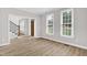Light-filled living room featuring wood-look floors, staircase, and large windows at 1003 Wicksteed Ct, Apex, NC 27502