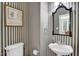 This vintage half bath is accentuated by striped wallpaper, vanity mirror, a pedestal sink, and decor at 1003 Wicksteed Ct, Apex, NC 27502