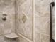 Close-up of a tiled shower featuring decorative inlays, a built-in seat, and a grab bar at 101 Temple Gate Dr, Cary, NC 27518
