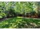 Lush backyard featuring a manicured lawn surrounded by mature trees and shrubbery at 103 Uxbridge Ct, Cary, NC 27513