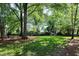 A spacious backyard featuring mature trees, lush green grass, and natural landscaping at 103 Uxbridge Ct, Cary, NC 27513