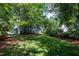 Spacious backyard with lush grass, mature trees, and blue siding house at 103 Uxbridge Ct, Cary, NC 27513