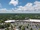 Wide view of a shopping plaza surrounded by abundant parking, and a verdant forest canopy, beneath a partly cloudy sky at 104 Deer Park Ln, Cary, NC 27518