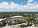 High angle view of a shopping center with spacious parking and tree-lined surroundings, under a blue sky with scattered clouds at 104 Deer Park Ln, Cary, NC 27518