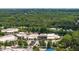 Aerial view of a shopping center with multiple stores and ample parking, surrounded by lush green trees and distant buildings at 104 Deer Park Ln, Cary, NC 27518