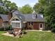 Backyard view with brick house featuring an outdoor patio with seating, surrounded by a well-manicured lawn at 104 Deer Park Ln, Cary, NC 27518