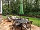 Outdoor patio with dining set and umbrella, surrounded by a lush, green lawn and trees at 104 Deer Park Ln, Cary, NC 27518