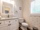 Charming powder room with elegant wallpaper, white vanity, marble countertop, and plantation shutters at 104 Deer Park Ln, Cary, NC 27518