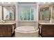 Bathroom with a soaking tub, dual vanities, and a window with privacy shutters at 10405 Veasey Mill Rd, Raleigh, NC 27615