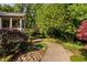 Landscaped backyard with brick pathway leading to the covered porch, surrounded by trees and greenery at 10405 Veasey Mill Rd, Raleigh, NC 27615