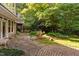 Backyard stone patio surrounded by lush landscaping, mature trees, and meticulous hardscaping, creating an inviting outdoor area at 10405 Veasey Mill Rd, Raleigh, NC 27615
