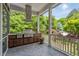 Covered outdoor kitchen with stainless grill, cabinetry, and overhead ventilation, offering picturesque views at 10405 Veasey Mill Rd, Raleigh, NC 27615