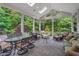 Open screened porch with dining and seating areas, ceiling fan, and picturesque wooded views at 10405 Veasey Mill Rd, Raleigh, NC 27615