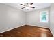 This bedroom features a ceiling fan, natural light from the window, and gleaming hardwood floors at 10816 Bent Branch Dr, Raleigh, NC 27603