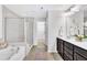 Bright bathroom featuring a soaking tub, glass enclosed shower, double vanity with dark wood cabinets and a walk-in closet at 1156 Craigmeade Dr, Morrisville, NC 27560