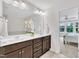 Bright bathroom featuring a double vanity with dark wood cabinets, ample lighting and a view into the bedroom at 1156 Craigmeade Dr, Morrisville, NC 27560