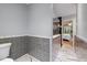 Bathroom with gray tiled wainscoting, marble floors, and a glass shower door, offering a spa-like feel at 119 Valleycastle Ct, Clayton, NC 27520