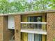 Two-story exterior view showcasing a balcony with outdoor seating, brick detail, and building address at 1200 Schaub Dr # G, Raleigh, NC 27606