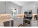 Well-lit kitchen boasts stainless appliances, double sink, stone countertops, and ample white cabinetry at 1312 Stonemoor Ct, Raleigh, NC 27606