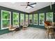 Bright sunroom with lots of windows, green trim, and views of the wooded backyard at 1312 Stonemoor Ct, Raleigh, NC 27606