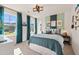 Comfortable bedroom with large windows, turquoise curtains, and colorful accent wall with themed décor at 148 Sugar Pine Drive, Franklinton, NC 27525