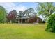 View of the brick home featuring large backyard and covered patio at 1517 Hodges Chapel Rd, Benson, NC 27504