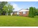 Lovely brick home featuring a well-manicured lawn and mature landscaping with trees and shrubbery at 1517 Hodges Chapel Rd, Benson, NC 27504