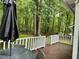 A tranquil view from the back deck with outdoor seating and an umbrella, overlooking a lush, wooded backyard at 1634 Hurdle Mills Rd, Roxboro, NC 27574